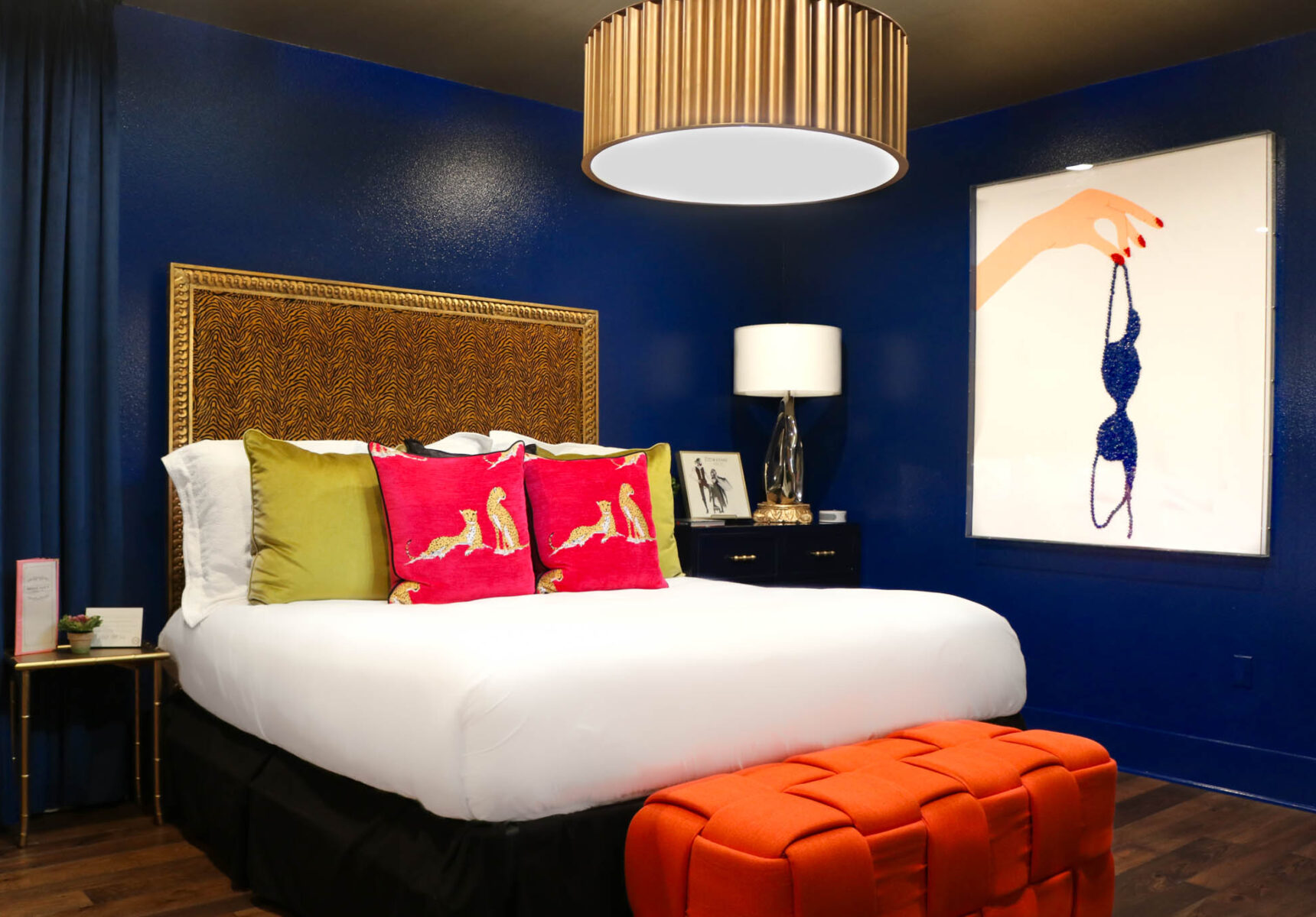 vinyl theme bedroom with colorful pillows on king bed and orange foot stool 