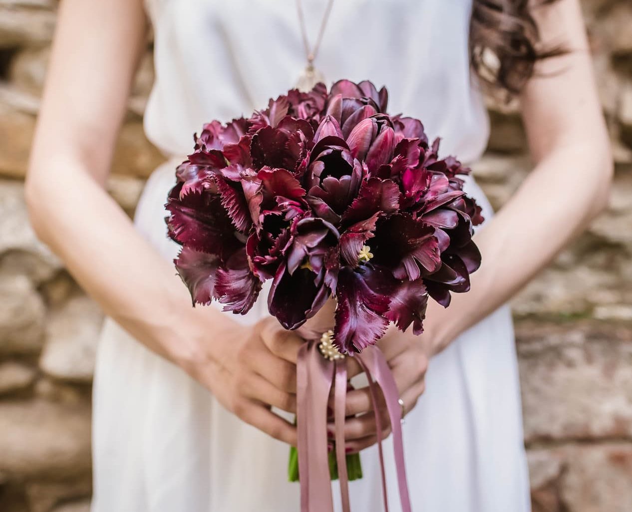 Bride holding a bouquet of maroon flowers