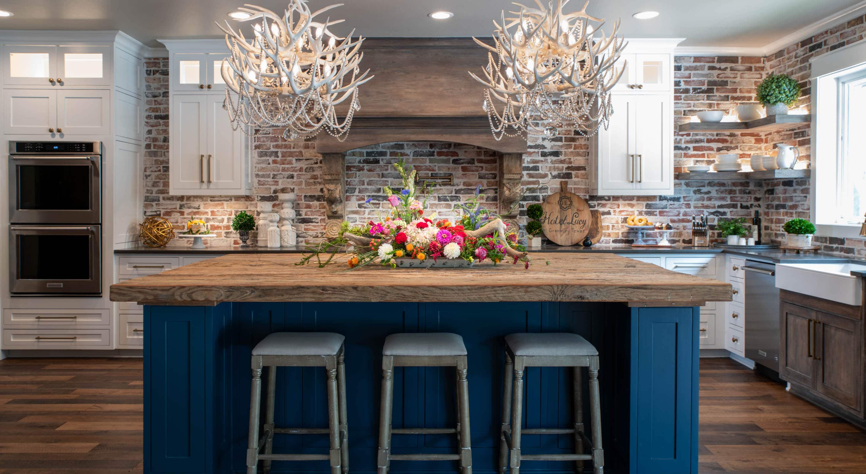 Big Lucy Kitchen with a reclaimed wood bar and three stools with two antler chandeliers