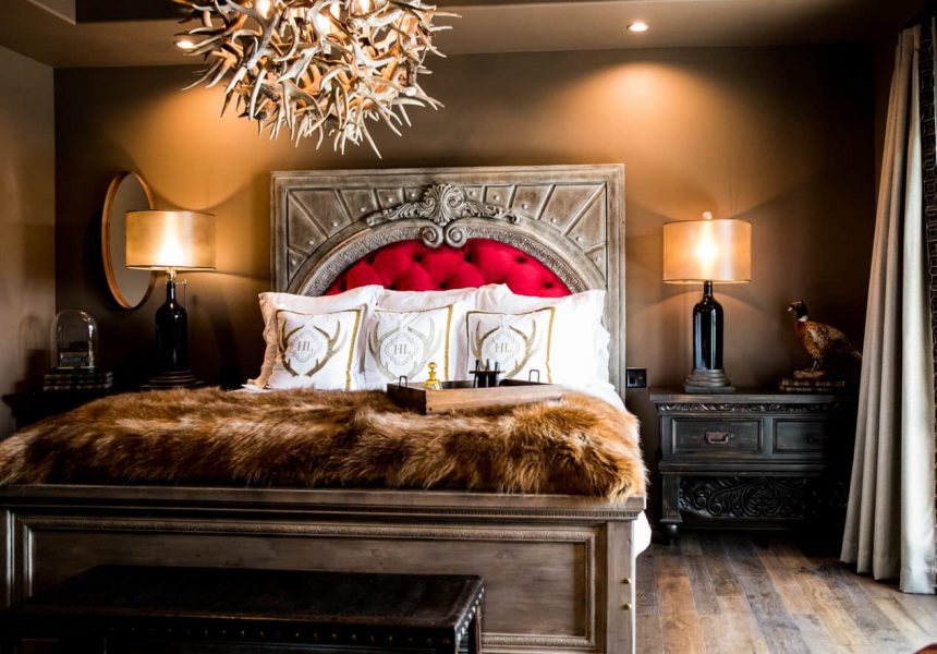 Spacious room with a king bed side tables with lamps and an antler chandelier