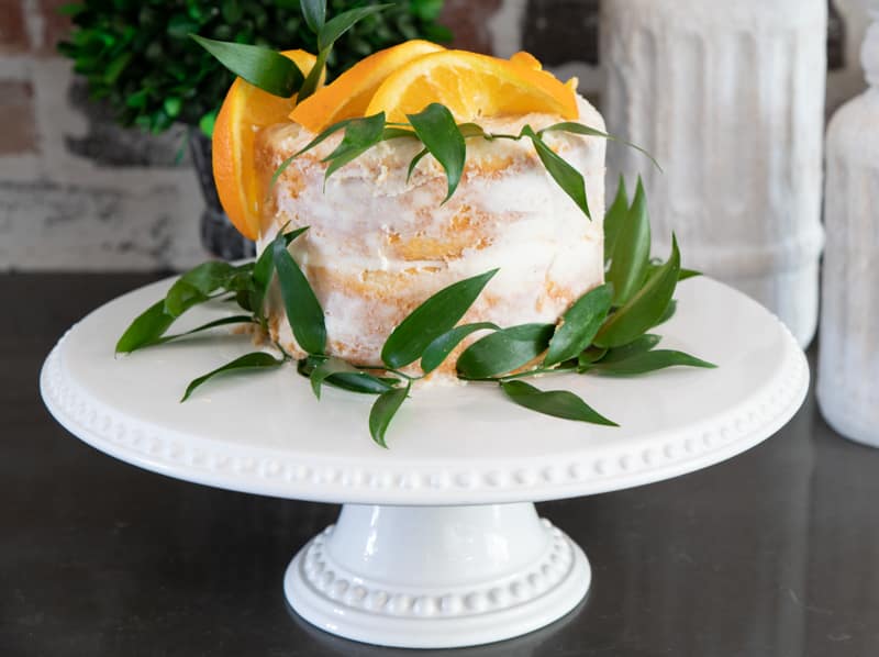 A small cake decorated with orange slices and orange leaves