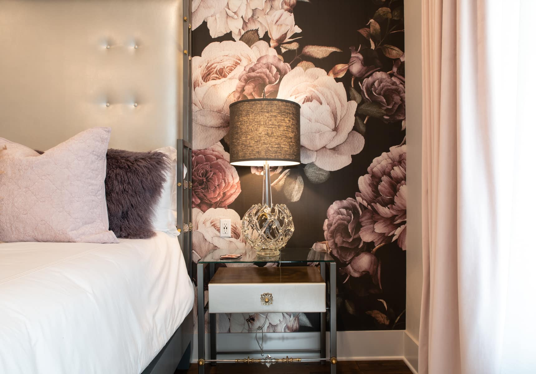 King bed with a glass end table and floral wall paper