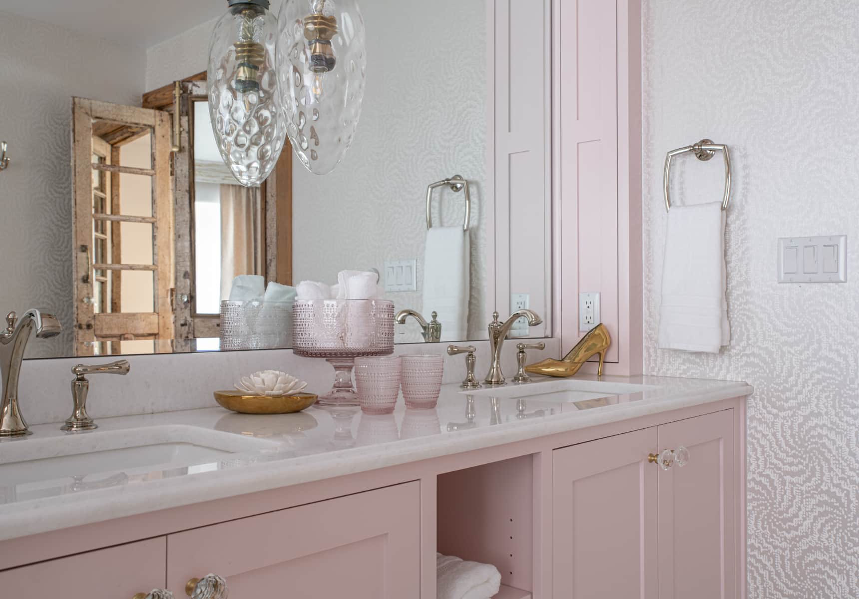 A bathroom with two sinks and light pink cabinets