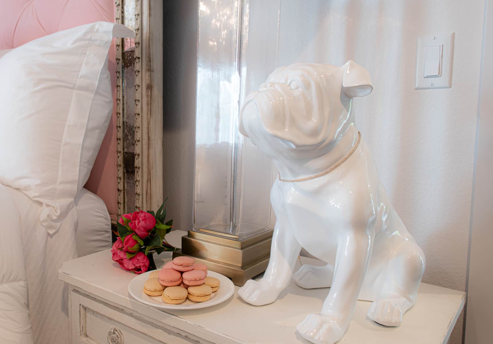 A small porcelain dog on a end table with a plate of french macaroons