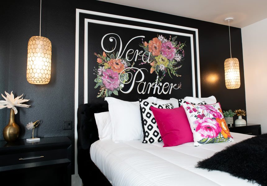 Bed in the Vera Parker room with white and black walls, pillows and lamps