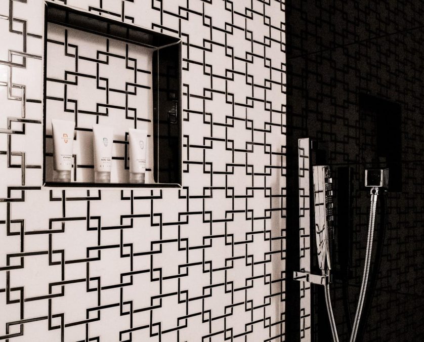 Walk-in shower with black and white geometric patterned tiles