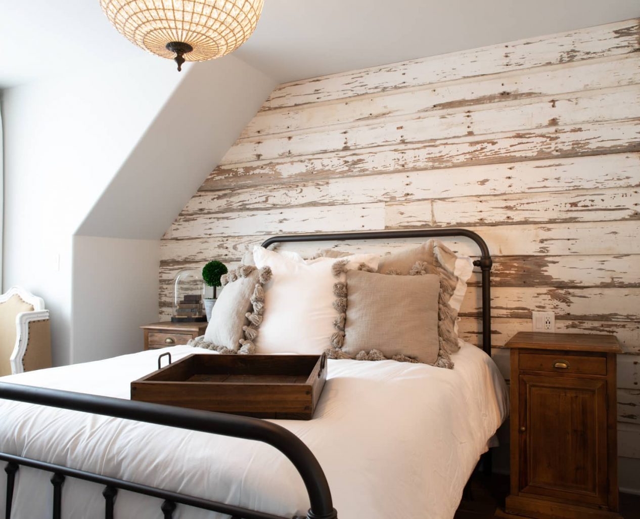 Queen bed in a room with a rustic wood plank wall and seating area near a window